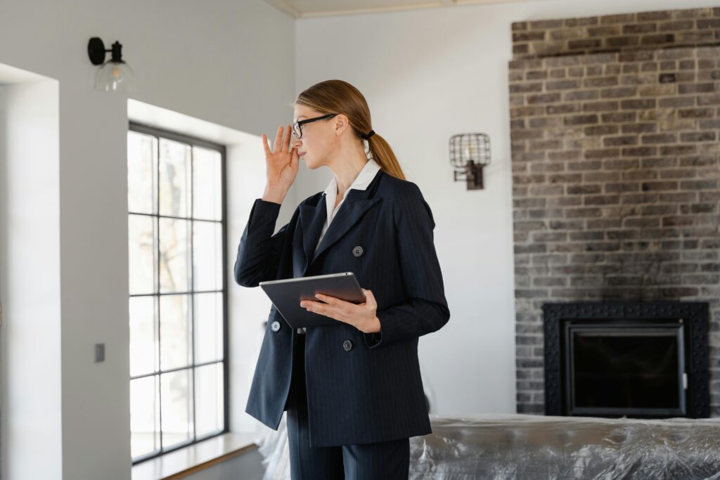 Woman in blazer with tablet in a modern home interior, symbolizing property viewing.